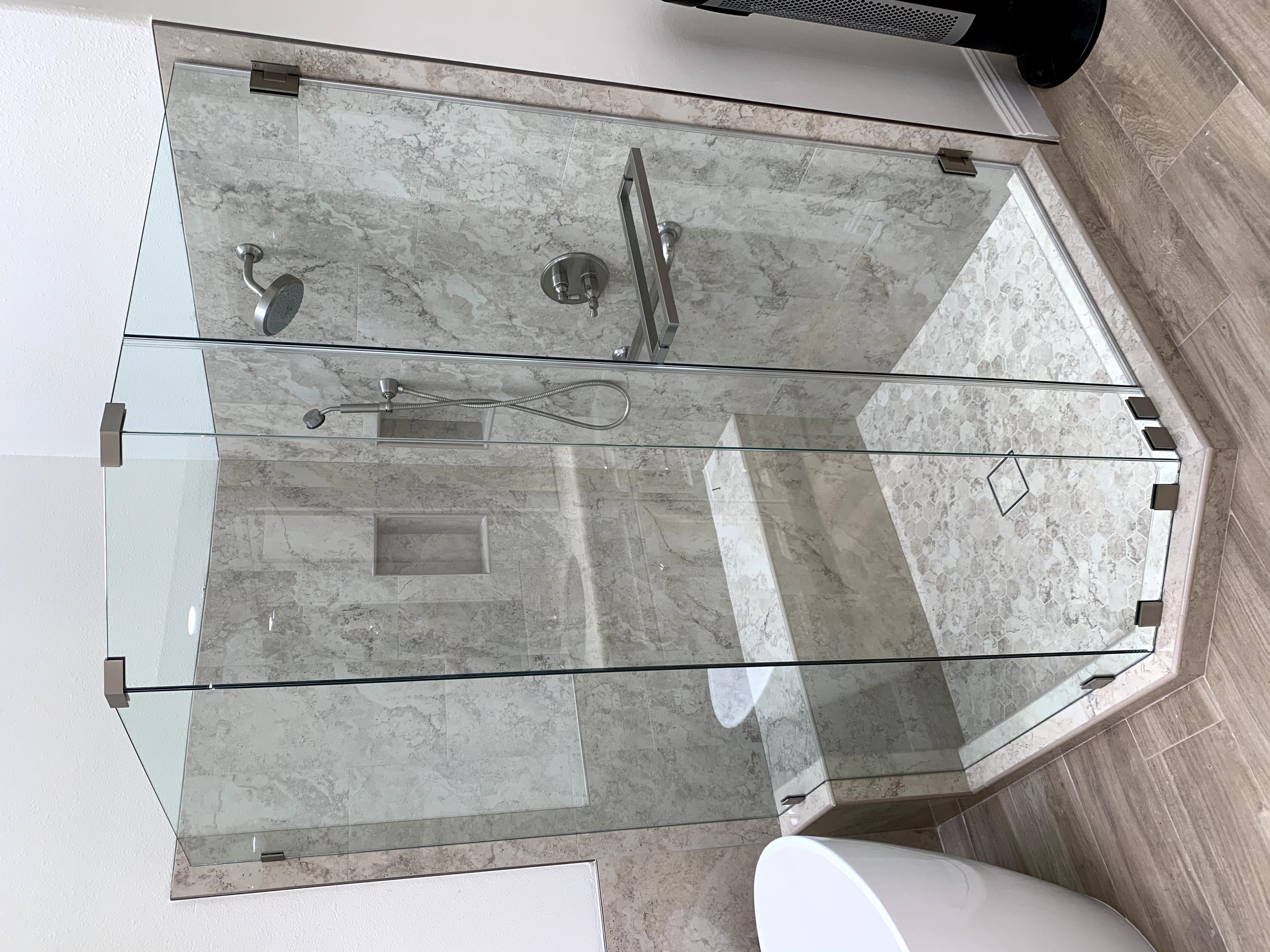 Custom shower door enclosure with four glass panels and one heavy shower door.